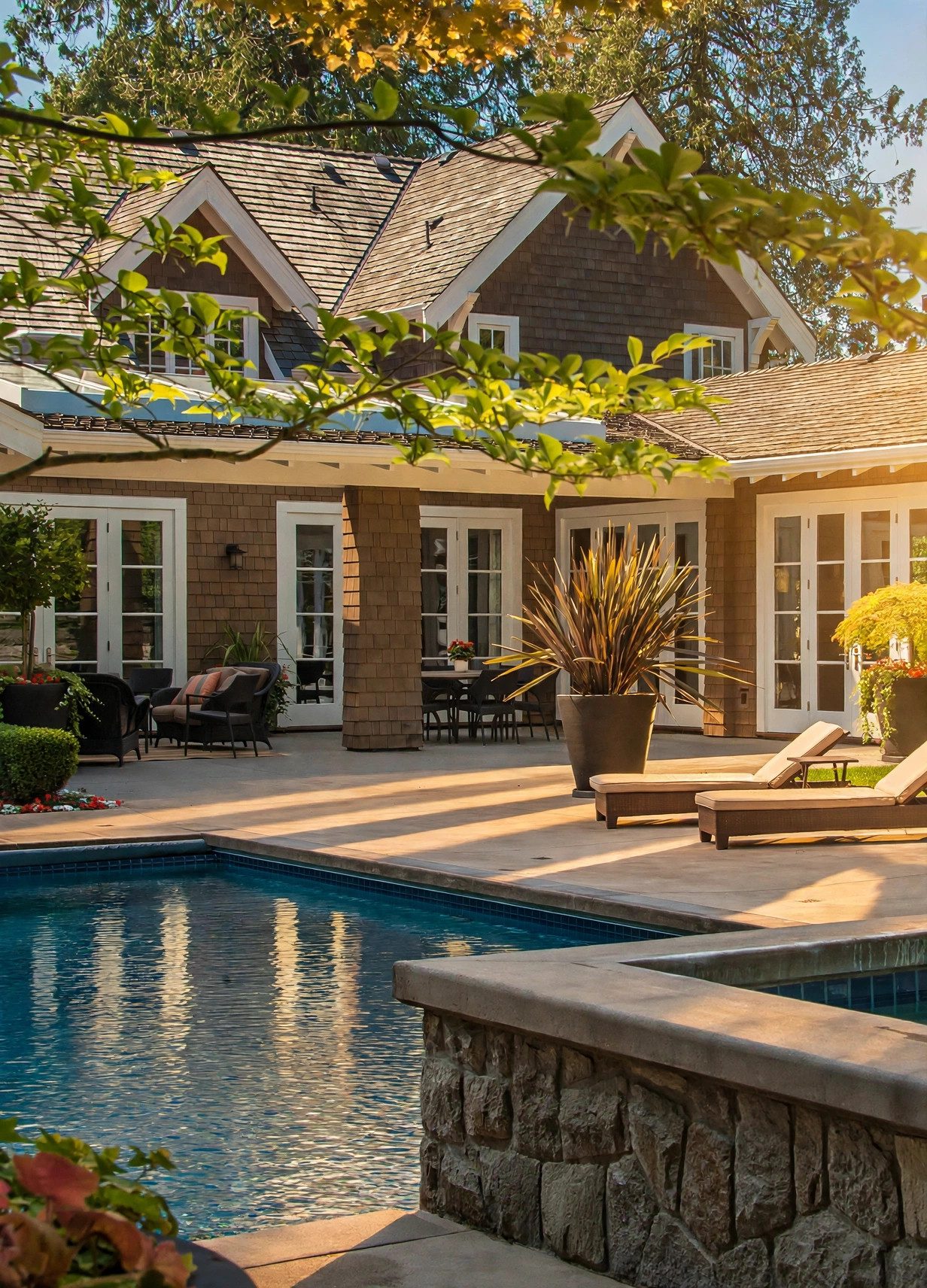 Craftsman-style home and pool framed by mature landscaping