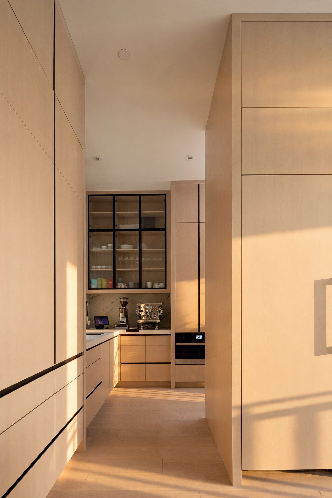 Warm oak coffee bar with integrated cabinetry in late-afternoon light